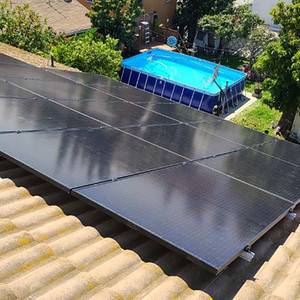 Black solar panels on a tile roof overlooking a backyard pool