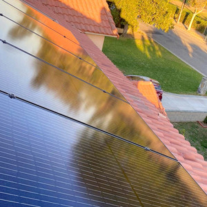 Close-up of solar panels on a red tile roof reflecting sunlight